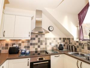 a kitchen with white cabinets and a clock on the wall at Squirrel Bank in Ambleside