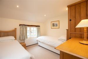 a bedroom with two beds and a desk with a lamp at Forest Cottage in Coniston
