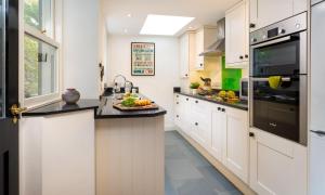 a kitchen with white cabinets and black counter tops at Greystones in Bowness-on-Windermere