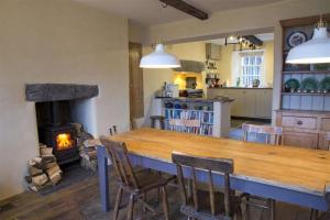 a kitchen with a large wooden table and a fireplace at Thomas Grove House in Penrith