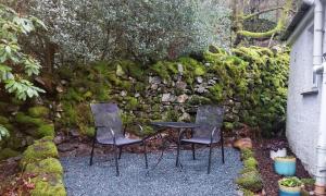 two chairs and a table in front of a stone wall at Helm Crag in Grasmere