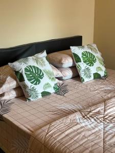 uma cama com almofadas verdes e brancas em PD VIP Pool View w WiFi - Anugerah Staycation em Porto Dickson