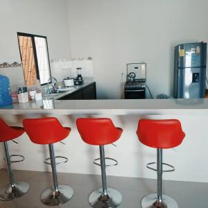 een keuken met vier rode barkrukken aan een balie bij Casa amoblada y cómoda en BALLENITA, Santa Elena. in Ballenita