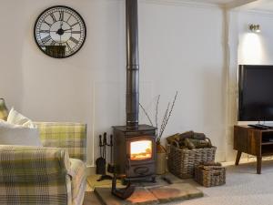a living room with a wood stove with a clock on the wall at The Old Butchers Shop in Wereham