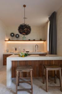 a kitchen with a sink and a counter with two stools at Unho Tulum in Tulum