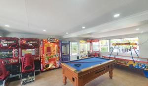 uma sala com jogos de fliperama e uma mesa de bilhar em Alex Beach Cabins and Tourist Park em Alexandra Headland