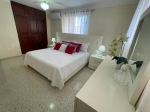 a bedroom with a white bed with red pillows at MView: Comfortable, great location, city view in Santiago de los Caballeros