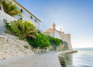 a cobblestone street next to the ocean and buildings at Rooms Sonja P in Rab