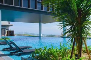 einen Pool mit Stühlen und einer Palme in der Unterkunft Seabreeze Seaview Super Cosy Stay Bali Residence in Malakka