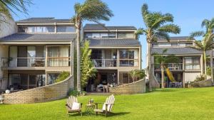 a large house with two lawn chairs and palm trees at Sunset at The Moorings in Soldiers Point