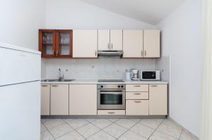 a kitchen with white cabinets and a stove top oven at Apartments Marija P Lopar in Lopar