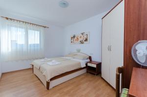 a white bedroom with a bed and a window at Apartments Marija P Lopar in Lopar