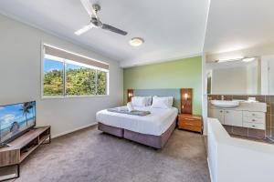 1 dormitorio con cama, lavabo y bañera en Airlie Summit Apartments, en Airlie Beach