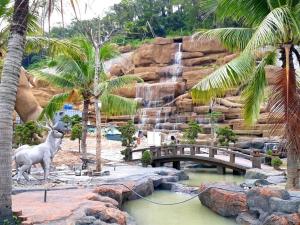 a zoo with a waterfall and a bridge and palm trees at Minh Hưng Motel in Ha Long