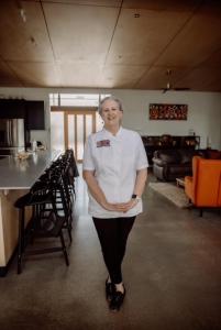 a woman is standing in a room with a kitchen at Tocumwal Chocolate School in Tocumwal