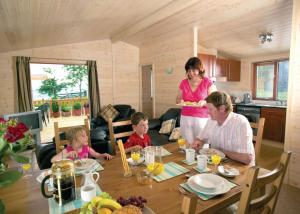 a woman and two children are sitting at a table at Belan Bach Lodges in Llanerfyl