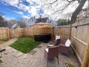 a backyard with chairs and an umbrella and a fence at NEW!! Lovely unit w/ PRIVATE Hot Tub and patio! in Laconia