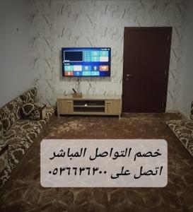 a living room with a television and a table with a sign at فيلا الراحة in Al Qunfudhah