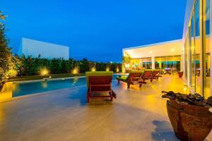 a swimming pool in a building with chairs and a building at Modern Tropical 4 Bedroom Pool Villa KH-B5 in Khao Tao
