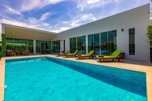 a swimming pool with green chairs next to a building at Modern Tropical 4 Bedroom Pool Villa KH-B5 in Khao Tao