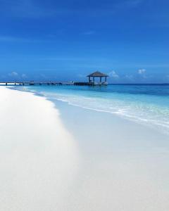 a white beach with a gazebo in the ocean at Paradisola in Fodhdhoo