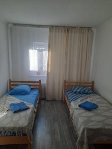 2 camas individuales en una habitación con ventana en Ohana Boutique, en Astana