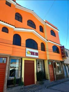 an orange building with red doors on a street at Sumac wasi in Chivay