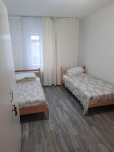 two beds in a room with wooden floors at Ohana Boutique in Astana