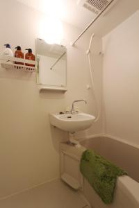 a white bathroom with a sink and a green towel at Shibuya-ku - Apartment / Vacation STAY 1130 in Tokyo