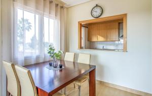 mesa de comedor con sillas y reloj en la pared en Amazing Apartment In Los Alczares With Kitchen, en Los Alcázares