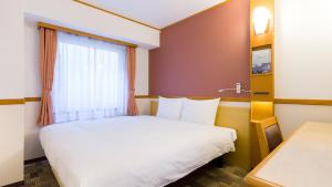 東京にある東横INN品川駅高輪口のベッドと窓が備わるホテルルーム