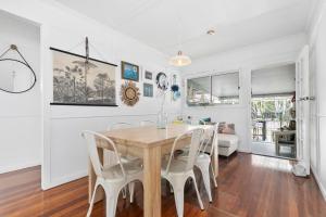 a dining room with a wooden table and white chairs at The Shack in Woorim