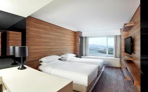 ein Hotelzimmer mit 3 Betten und einem Fenster in der Unterkunft Grand Walkerhill Seoul in Seoul