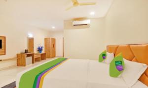 艾哈迈达巴德Hotel Fun Regency Vitthalapur Gujarat的卧室配有一张白色大床,提供绿色和色彩缤纷的枕头