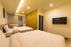a hotel room with two beds and a flat screen tv at YY Elleys Home in Jiaoxi