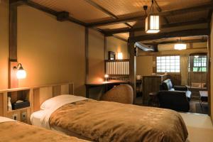 1 Schlafzimmer mit 2 Betten, einem Schreibtisch und einem Zimmer in der Unterkunft Kurokawa Onsen Oyado Noshiyu in Minamioguni