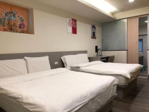 two beds in a hotel room with white sheets at YY Elleys Home in Jiaoxi