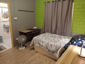 a bedroom with a bed and a desk with a fan at Young and Beautiful in Bangkok