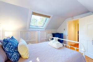 a bedroom with a bed with blue pillows and a window at Wisteria Cottage in Camden