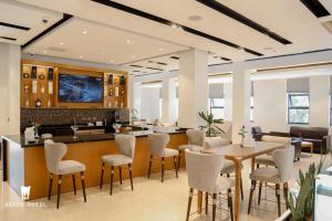 a restaurant with a bar with white chairs and tables at Hayes Hotel, Addis Ababa in Addis Ababa