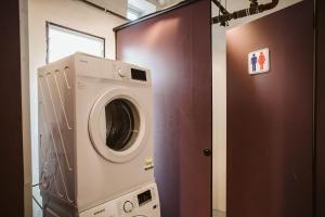 a washing machine in a room next to a door at 7 Wonders Hostel @ Boat Quay in Singapore