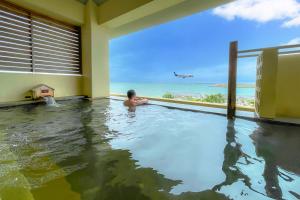 豊見城市にある琉球温泉 瀬長島ホテルの海を背景にしたスイミングプールの男
