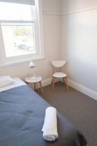 ein Schlafzimmer mit einem Bett, einem Fenster und einem Stuhl in der Unterkunft Seven Seas Hotel in Carrington