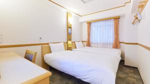 a room with two beds and a window at Toyoko Inn Hokkaido Okhotsk Abashiri Ekimae in Abashiri