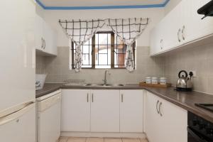 uma cozinha branca com um lavatório e uma janela em La Pirogue 1 em Ballito