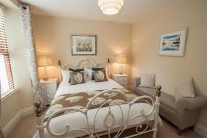 a bedroom with a white bed and a chair at Acorn Cottage in Ambleside