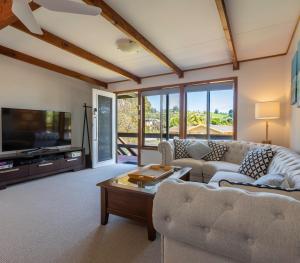uma sala de estar com um sofá e uma televisão em Surf Beach Escape em Surf Beach