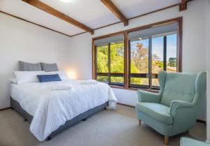 a bedroom with a bed and a chair and windows at Surf Beach Escape in Surf Beach