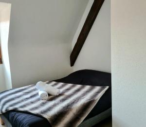 uma cama com um cobertor às riscas e dois rolos de papel higiénico em Auberge SYRA/ Proche Europa Park em Marckolsheim