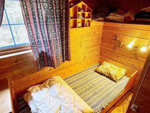 a small bed in a wooden room with a window at Three-Bedroom Holiday home in Åkra in Kyrping